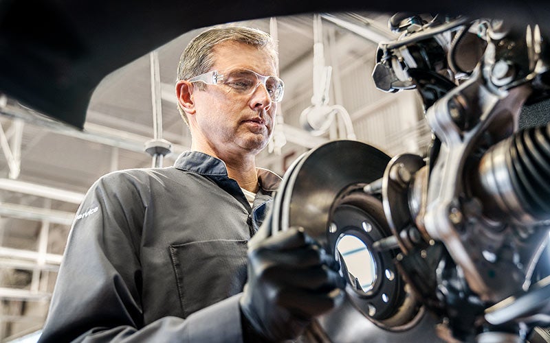 Certified Service technician inspecting a brake rotor and caliper assembly