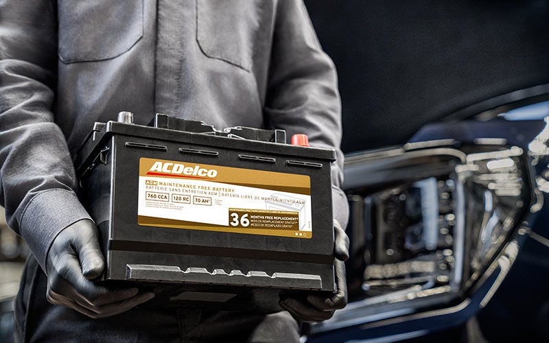 Technician holding an ACDelco 36-month automotive battery